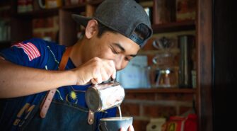 a barista pours milk into a cup