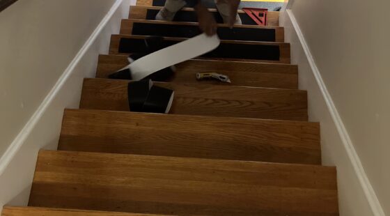 A contractor lays grip strips on a flight of stairs