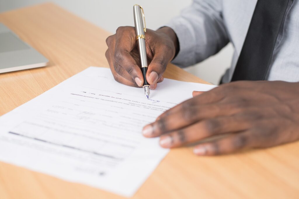 brown-skinned hands writing in pen on a piece of paper