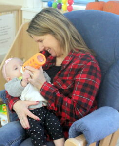 Educator in a rocking chair feeding a baby a bottle