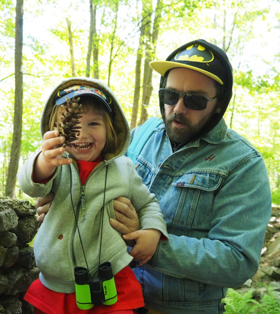 Head Start child holding up a pinecone while his father supports him